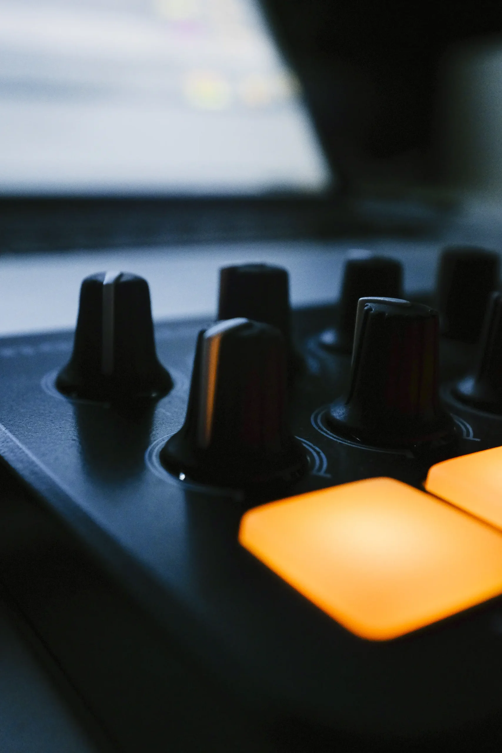 Controles y pads iluminados de un equipo de producción musical en primer plano